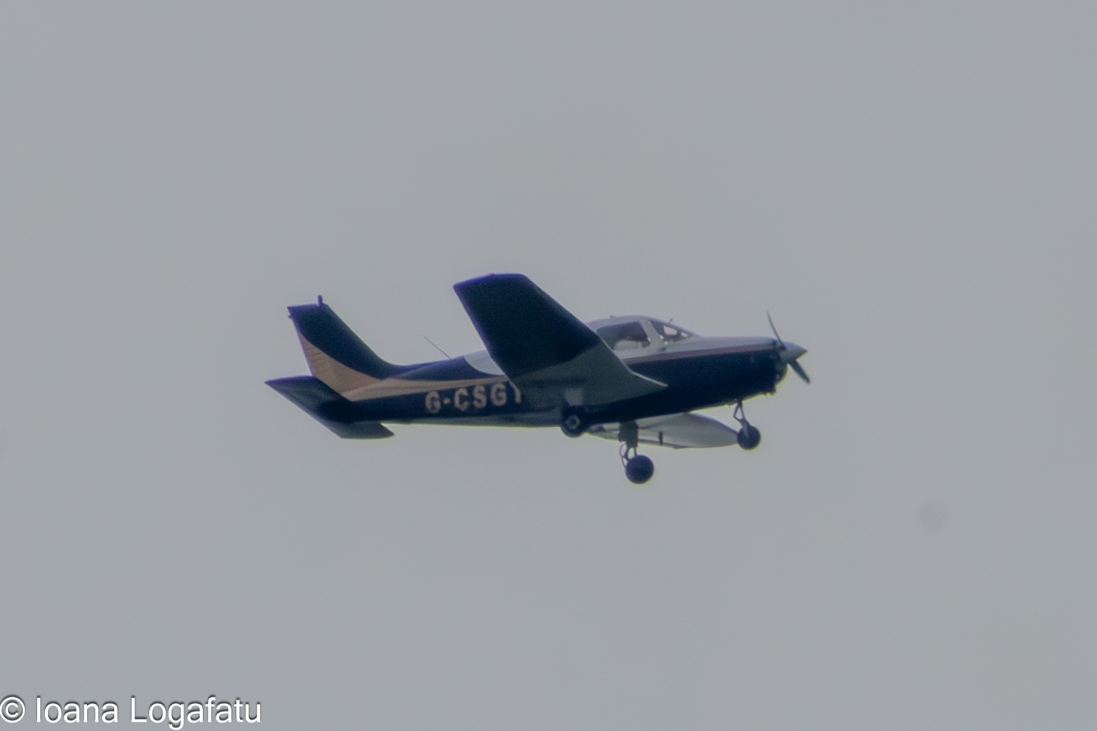 Small aircraft glides through the overcast sky